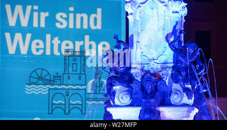 Augsburg, Deutschland. 06 Juli, 2019. Das Augustus Brunnen ist beleuchtet und auf der Fassade von der Verwaltung der Stadt der Schriftzug "Wir Gebäude sind Welterbe" projiziert wird. Augsburg wurde von der UNESCO in die Liste des Erbes der Welt wegen seiner historischen Wasser enthalten. Quelle: Stefan Puchner/dpa/Alamy leben Nachrichten Stockfoto