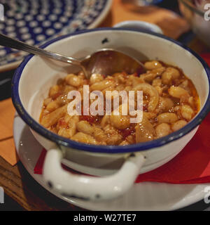 Nahaufnahme aus einer Schüssel "Fagioli con le cotiche' (im römischen Stil Schweinefleisch und Bohnen), mit Bohnen in Tomatensoße geschmort mit Streifen aus Schweineschwarten hergestellt. Stockfoto