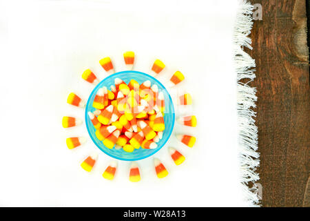 Candy corn in blauer Schüssel, auf einer weißen Serviette auf einem hölzernen Tischplatte positioniert Stockfoto