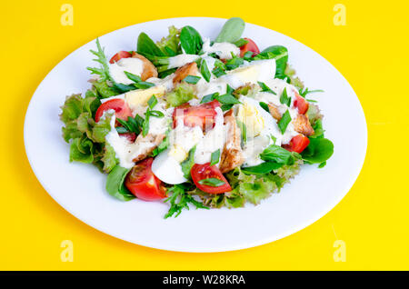 Salat Salat, Ei, Huhn, Mayonnaise auf weiße Platte auf gelbem Hintergrund Stockfoto