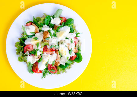 Salat Salat, Ei, Huhn, Mayonnaise auf weiße Platte auf gelbem Hintergrund Stockfoto