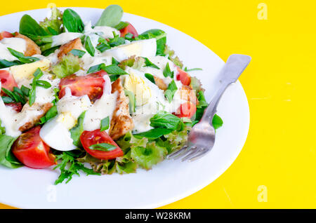 Salat Salat, Ei, Huhn, Mayonnaise auf weiße Platte auf gelbem Hintergrund Stockfoto