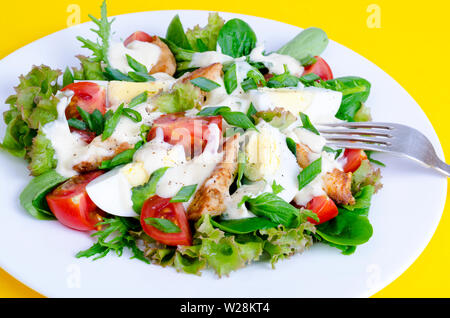 Salat Salat, Ei, Huhn, Mayonnaise auf weiße Platte auf gelbem Hintergrund Stockfoto