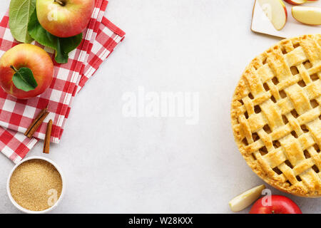 Hausgemachte Apfelkuchen mit Gitter oben und Zutaten auf graue Tabelle. Traditionelle amerikanische saisonale Gebäck Hintergrund. Kopieren Sie Platz. Stockfoto