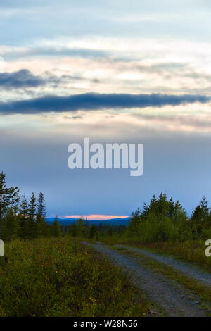 Orange glühen und geschichteten Wolken, von einer Straße in der Nähe von Granbergsliden, Schweden gesehen. Stockfoto