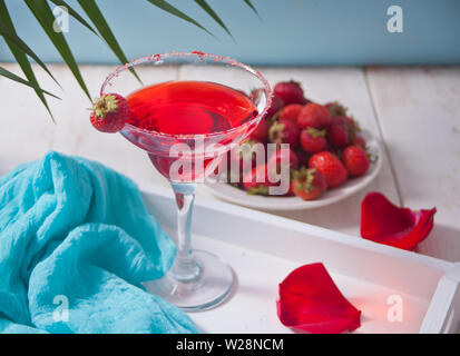 Zwei rote frischen exotischen alkoholfreien Cocktail in Klarglas, Rosenblätter und Platte mit Erdbeere unter dem palm leaf für romantische tropischen Abendessen Stockfoto