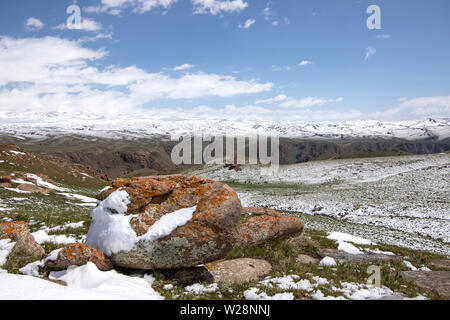 Pferde grasen auf einem schneebedeckten Weide. Am Horizont, schneebedeckten Bergen. Der Himmel in den Wolken. Reisen. Kirgisistan Stockfoto