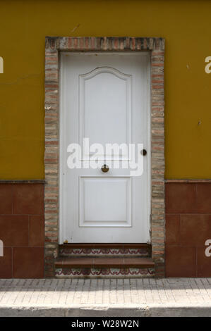 Weiße Eingangstür mit Gelb bemalte Fassade und die rötliche Fliesen Stockfoto