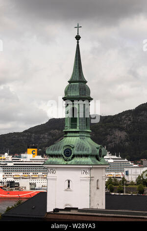 Der Turm der Kirche Nykirken mit einem Kreuzfahrtschiff im Hafen im Hintergrund in Bergen, Norwegen. Stockfoto