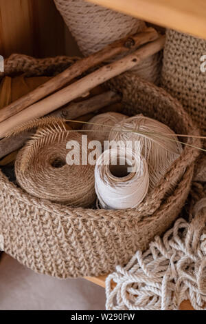 Macrame, Baumwolle und Hanf Seile in Strängen. Häkeln, Verrechnung kunsthandwerkliche Objekte in einem Korb aus Jute Stockfoto