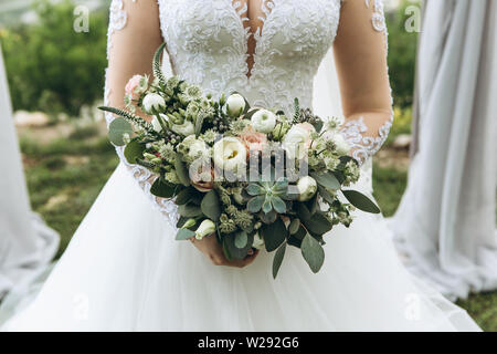 Eine Braut in einem weißen Kleid eine wunderschöne Hochzeit Bouquet. Frische Blumen, darunter Pfingstrosen Rosen. Hochzeit Feier. Stockfoto