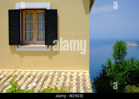 Restauriertes Haus gelb lackiert sun Aufhellung der Wände mit einer großartigen Aussicht aufs Meer im alten malerischen Dorf Afionis Korfu Stockfoto