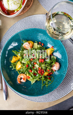 Fantastisch, frisch und lecker Salat mit Garnelen auf dem Tisch in einer schönen Schale mit einem Glas Wein. Gesunde Ernährung, richtige Ernährung, Gourmet Stockfoto