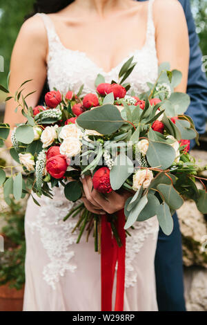 Die Braut hält in ihrer Hand eine wunderschöne Hochzeit Blumenstrauß einschließlich päonien Rosen. Hochzeit Feier. Stockfoto