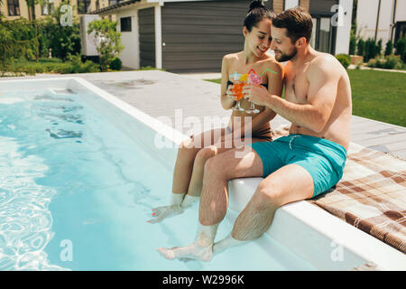 Schöne heteroseksual paar Sommer ausruhen. Der Mann und die Frau sitzen in der Nähe von Pool und mit frischen Cocktail Stockfoto