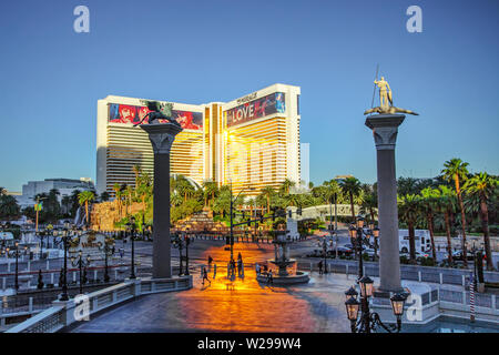 Las Vegas, Nevada, USA - Mai 6, 2019: Touristen Überqueren einer verkehrsreichen Straße auf dem Las Vegas Boulevard bei Sonnenaufgang mit dem Mirage Resort und Casino. Stockfoto