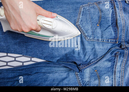 Foto von Mann bügeln blaue Jeans an Bord Stockfoto