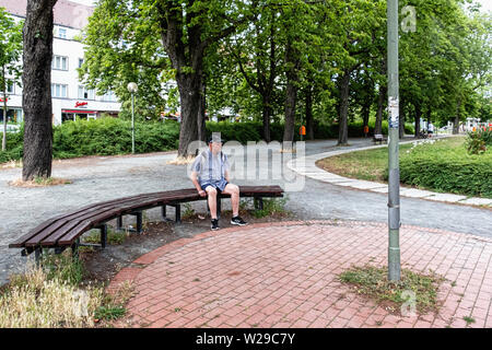 Ältere männliche Touristen auf der Werkbank unter schattigen Bäumen auf Breitenbachplatz, Dahlem, Berlin sitzen Stockfoto