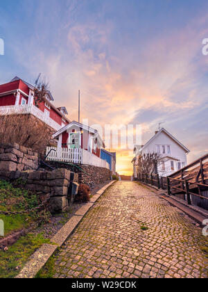 Fjällbacka, Schweden 01/12-18. Einer netten Straße im malerischen Fjällbacka. Die Sonne in der Ferne Färbung der Wolken. Stockfoto