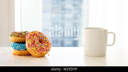 Donuts und Kaffee zum Frühstück. Bunte Donuts und Kaffee auf weißer Tisch. Nähe zu sehen. Stockfoto