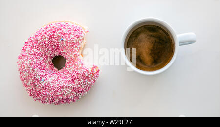 Donut und Kaffee. Rosa Donut und Espresso Kaffee auf weiße Farbe Hintergrund isoliert. Ansicht von oben Stockfoto