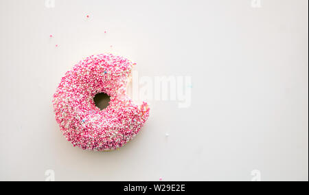 Donut mit Biss. Einen Donut mit rosa und weißen Dekoration auf weiße Farbe Hintergrund isoliert. Ansicht von oben, kopieren Raum Stockfoto