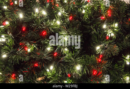 Beleuchteter Christbaum Hintergrund. In der Nähe von Weihnachten Baum mit bunten Lichtern und einem Abstauben des frischen Schnee Stockfoto