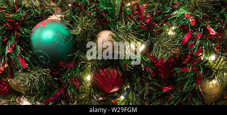 Festliche Hintergrund. Weihnachtsbaum mit Ornamenten verziert und mit bunten Lichtern in Panoramablick Orientierung beleuchtet Stockfoto