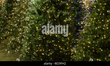 Kommissionierung, die Perfekten Weihnachtsbaum. Reihe von beleuchteten künstliche Weihnachtsbäume zum Verkauf Stockfoto