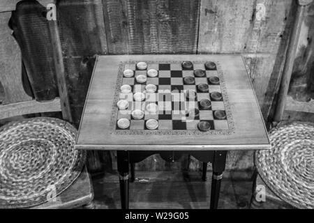 Spiel Der Kontroller. Traditioneller Holzschachbretttisch im Vintage-Stil mit Hockern in einem ländlichen Laden. Stockfoto