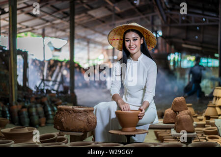 Handwerker der Frauen in der Vietnamesischen weiße Kleider und lokalen Weisheit Keramik erstellen Gläser und Vorbereitung im Brennofen brennen Stärke zu erstellen Stockfoto