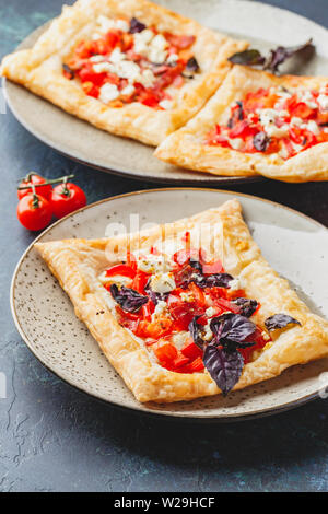 Blätterteig Törtchen mit Tomaten, süßer Paprika, Salami, Fetakäse und lila Basilikum. Close Up. Stockfoto