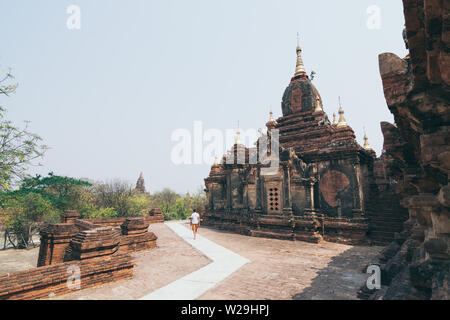 Kaukasische Mann im weißen Hemd zu Fuß neben dem buddhistischen Tempel von Bagan, Myanmar. Stockfoto