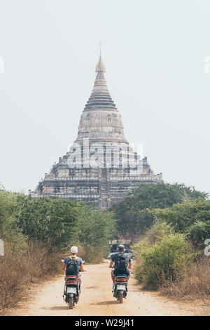 Junges Paar reiten Elektroroller in Richtung Shwesandaw Pagode der alten Tempelanlage Bagan in Myanmar Stockfoto