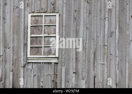 Texturierte Scheune Wand Hintergrund. Verwitterten grauen Scheune wand Fassade mit Verbrettert Fenster. Stockfoto