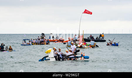 Brighton UK 7. Juli 2019 - die Wettbewerber sich auf hoher See aus Brighton Beach während dieser Jahre Paddeln Rund um die Pier Beach Festival in Brighton. Die jährlichen Paddel Rund um die Pier ist mittlerweile das größte kostenlose Beach Festival in Europa Geld für verschiedene Nächstenliebe einschließlich Surfers gegen Abwasser. Foto: Simon Dack/Alamy leben Nachrichten Stockfoto