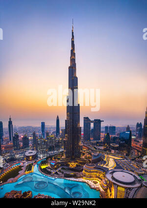 Dubai, Vereinigte Arabische Emirate - Juli 5, 2019: Burj Khalifa steigen über Dubai Mall und Brunnen durch die moderne Innenstadt von Gebäuden umgeben, oben
