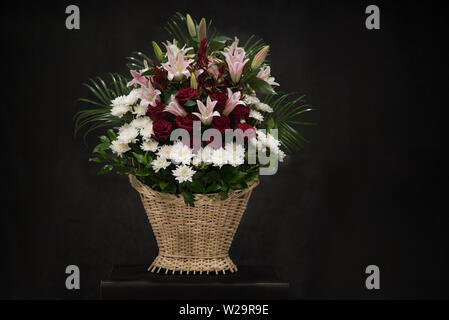 Rituelle Begräbnis Korb mit Blumen auf schwarzem Hintergrund. Die Blume Anordnung der Blumen im Korb ist für Begräbnisse und Lesezeichen verwendet. Mourni Stockfoto