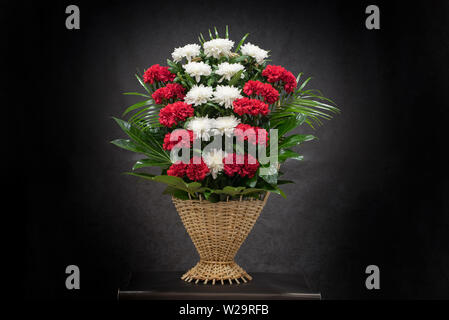 Rituelle Begräbnis Korb mit Blumen auf schwarzem Hintergrund. Die Blume Anordnung der Blumen im Korb ist für Begräbnisse und Lesezeichen verwendet. Mourni Stockfoto