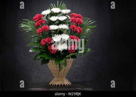 Rituelle Begräbnis Korb mit Blumen auf schwarzem Hintergrund. Die Blume Anordnung der Blumen im Korb ist für Begräbnisse und Lesezeichen verwendet. Mourni Stockfoto