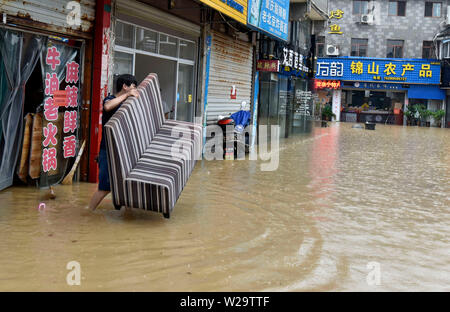 Fujian, China. 07 Juli, 2019. Ein Mann übergibt ein Möbelstück aus seinem überfluteten Shop nach einer Reihe von intensiven Regenfällen in das Grafschaft Sanming, im Südosten der chinesischen Provinz Fujian, 7. Juli 2019. Quelle: Xinhua/Alamy leben Nachrichten Stockfoto