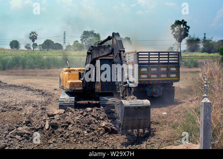 Tieflöffel graben zu Boden im Dump Truck an der Baustelle füllen. Stockfoto