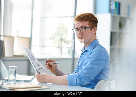 Ernsthafte junge Wirtschaftswissenschaftler in Brillen Analyse der Papiere Stockfoto