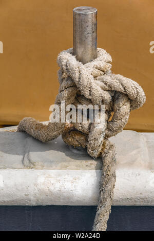 Nahaufnahme der alten natürlichen Seil um Edelstahl Säule auf einem Fischerboot gebunden. Stockfoto