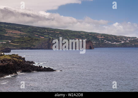 Oben auf der Klippe, die durch eine Wiese. Ruhigen Wasser des Atlantischen Ozeans. Bewölkter Himmel. Frühling im Norden von Sao Miguel, Azoren, Portugal. Stockfoto