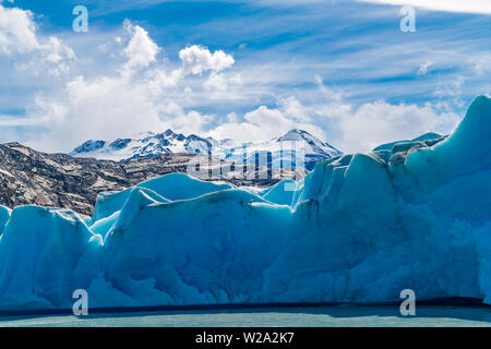 Blauer Eisberg der Grey Gletscher auf der Grauen See und den verschneiten Berg bei Torres del Paine National Park im südlichen chilenischen Patagonien, Chile Stockfoto