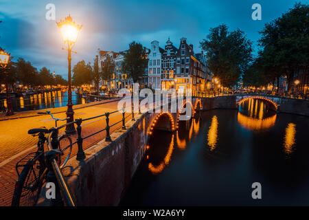 Night city Blick auf Amsterdam. Beleuchtete Brücke an der Herengracht. Typische holländische Häuser in der Stunde leuchtet, Holland, Niederlande Stockfoto