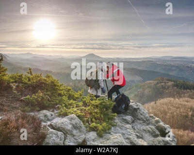 Silhouette Menschen und Freundin schießen Sonnenuntergang auf dem Tafelberg. Fotograf mit dem Auge am Sucher der Kamera auf Stativ Aufenthalt auf einer Klippe und nimmt Pho Stockfoto