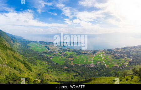 Antenne: Toba-See und die Insel Samosir Blick von oben Sumatra Indonesien. Riesige vulkanische Caldera von Wasser bedeckt, traditionelle Batak Dörfer, grüne Reis Stockfoto