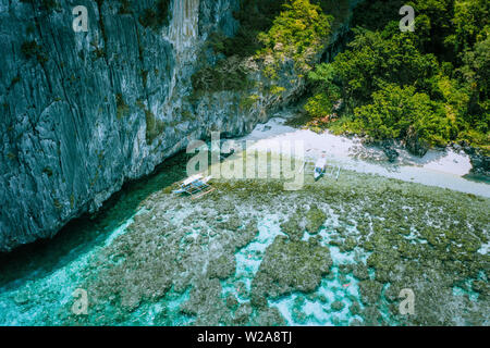 Luftbild der Banca Boote am White Sand Beach und Menschen Schnorcheln über bunte Korallenriffe in El Nido. Philippinen Stockfoto